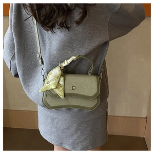 Detail of green canvas handbag with D-letter metal buckle and floral silk scarf handle