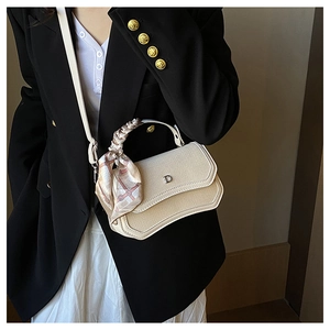 Detail view of woven texture handbag with decorative silk scarf and metallic D buckle