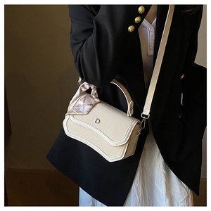 Detail view of cream fabric shoulder bag with metal D-buckle and pink scarf on the handle