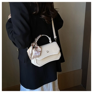 Detail shot of cream shoulder bag with fabric texture and silk scarf handle detail