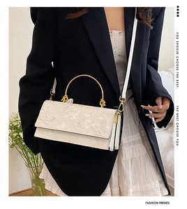 Lace handbag with butterfly embroidery and golden metal handle held by model