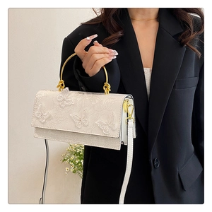 Detail of white lace handbag with 3D butterfly embroidery and golden metal handle