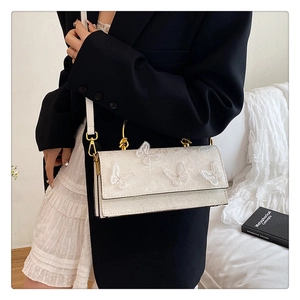 Detailed view of white lace crossbody bag with 3D butterfly embroidery and metal handle