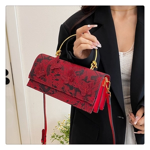 Detailed close-up of 3D butterfly embroidery on red lace handbag with gold metal handles