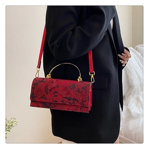 Detail of red lace handbag with butterfly embroidery and golden ring handle