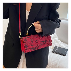Close-up of red lace bag with 3D butterfly and rose embroidery and gold metal handle