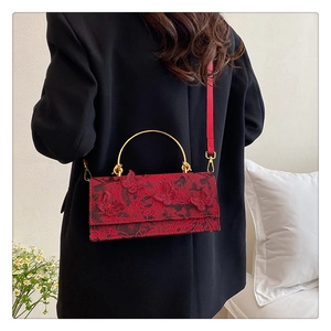 Macro detail of red lace bag featuring exquisite butterfly embroidery and golden handle