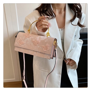 Detailed shot of pink crossbody bag with lace butterfly embroidery and gold handle