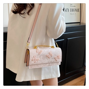 Close-up of pink lace handbag featuring 3D butterfly embroidery and gold metal handle