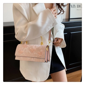 Detail of pink lace handbag featuring 3D butterfly embroidery and gold metal handle