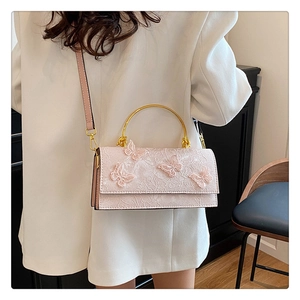 Detail of pink lace handbag with butterfly embroidery and golden metal ring handle