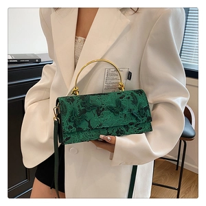Detail of vintage green butterfly lace bag with gold ring handle and leather texture