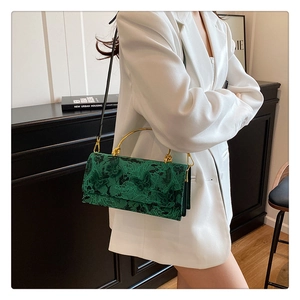 Detailed view of green lace handbag with butterfly embroidery and golden metal handle
