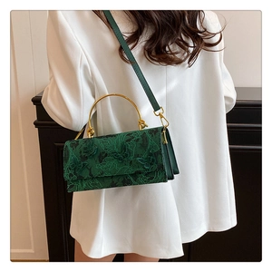Detail of green floral lace bag with golden circular handle and butterfly embroidery