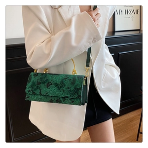 Close-up of butterfly embroidery and golden ring handle on dark green lace square handbag