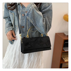 Close-up of black lace clutch with 3D butterfly embroidery and gold metal handle