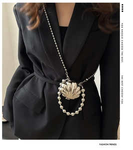 Detail of silver shell-shaped mini bag with glossy metallic texture and pearl chain