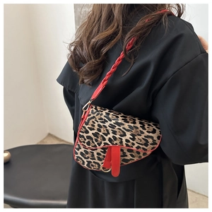 Détail du sac selle léopard avec bordures en cuir rouge et bandoulière tissée rouge