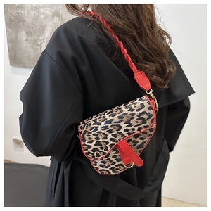 Détail du sac selle à motif léopard avec bordure en cuir rouge et bandoulière tissée