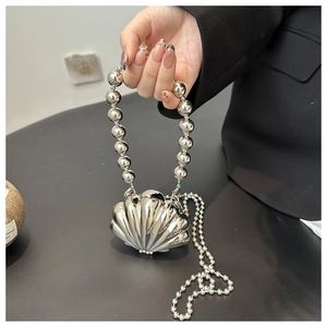 Detailed view of silver shell-shaped evening bag with metallic texture and beaded handle