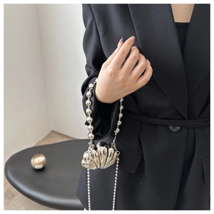 Mini silver shell bag with metallic mirror finish and pearl chain strap on model