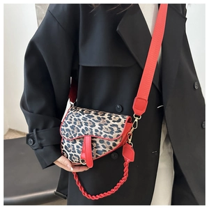 Détail du sac selle à imprimé léopard avec bordure en cuir rouge et bandoulière