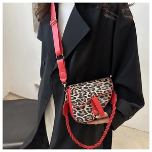 Détails du sac selle léopard avec bordure en cuir rouge et bandoulière sur une veste noire