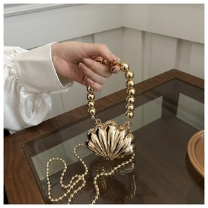 Detailed view of a golden shell-shaped mini bag with metallic texture and beaded handle