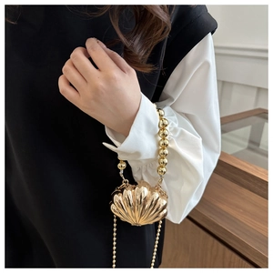 Detail view of a gold shell-shaped evening bag featuring a beaded handle and metal chain strap