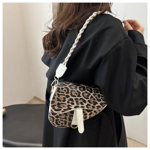 Détail du sac selle léopard avec bandoulière tissée blanche et boucles dorées