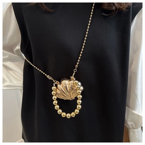 Detail of a mini golden shell bag with large pearl handle and beaded chain strap