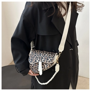 Détail du sac selle à motif léopard avec bordures en cuir blanc et chaîne tressée