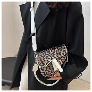 Détail du sac selle à motif léopard avec poignée tressée blanche et boucles dorées