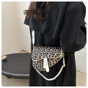 Détail du sac selle léopard avec chaîne tressée blanche porté par un mannequin