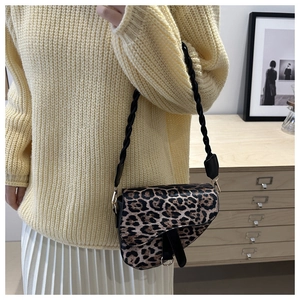 Détail du sac selle léopard avec bandoulière tissée et boucles dorées sur le mannequin