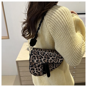 Détail du sac selle à motif léopard avec bordure en cuir noir et boucles métalliques