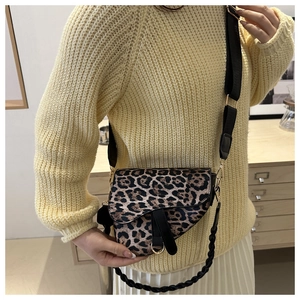 Sac selle chic à imprimé léopard porté avec un pull beige dans un décor intérieur
