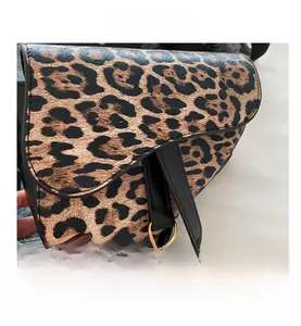 Gros plan du sac selle léopard avec anneau doré et bandoulière en cuir noir