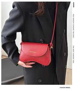Detail shot of a red leather crescent shoulder bag paired with a stylish black blazer outfit