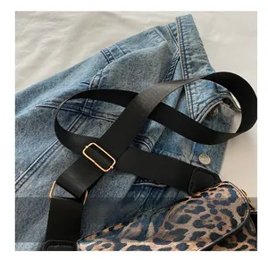 Détail de la bandoulière tressée noire réglable et boucle en métal doré sur le sac léopard