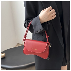 Detail of red leather crossbody bag with gold Fashion lettering and curved bottom edge