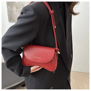 Close-up of red half-moon crossbody bag with gold lettering on black blazer background