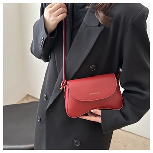 Detail of red leather crossbody bag with curved base and golden fashion logo print