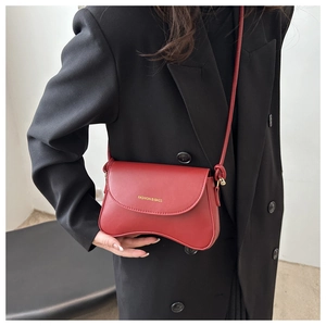 Close-up of vintage red PU leather shoulder bag with gold logo text on black suit