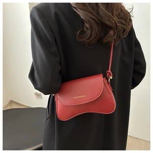 Red matte leather bag worn with black blazer, showing a stylish crossbody strap detail