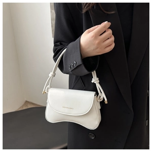 Detail of white glossy leather bag with knotted handle and gold lettering