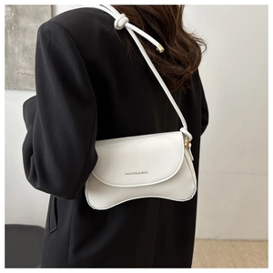 Detail of white patent leather shoulder bag with FASHION & BAGS print on a black blazer