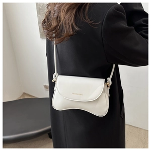 Detail of white leather crossbody bag with knot shoulder strap and gold lettering