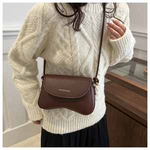 Close-up of brown PU crossbody bag with unique wavy bottom and gold logo detail