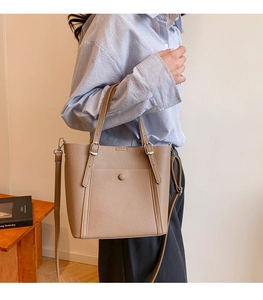 Detail of khaki lychee grain leather tote bag with vintage metal buckle and adjustable strap
